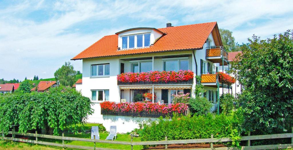 ein weißes Haus mit roten Blumen davor in der Unterkunft Haus Kees - Wohnung 1 in Kressbronn am Bodensee