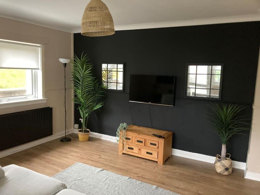 a living room with a flat screen tv on a black wall at Budget friendly apartment with stairs Near Glasgow airport and Loch Lomond in Clydebank