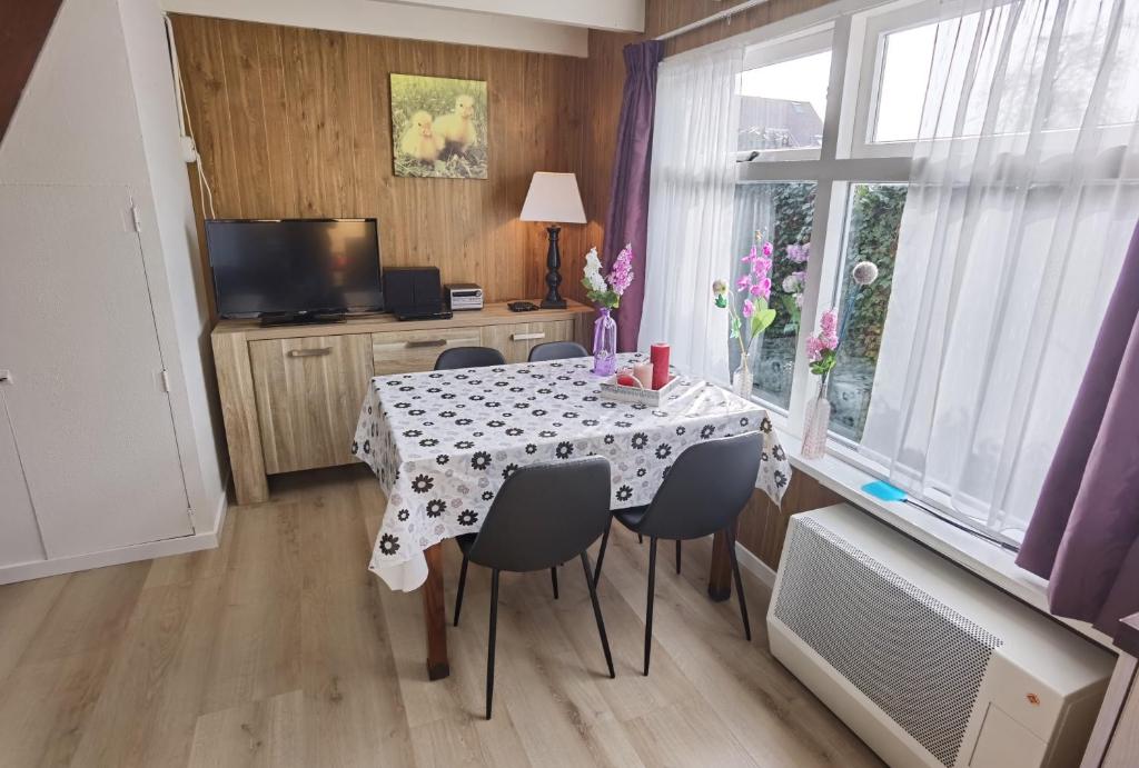 a dining room with a table and chairs and a window at ALO43 renovated holiday home in Aagtekerke
