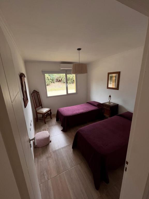 1 dormitorio con 2 camas, silla y ventana en Cabaña Caballeriza La Prestancia en Tandil