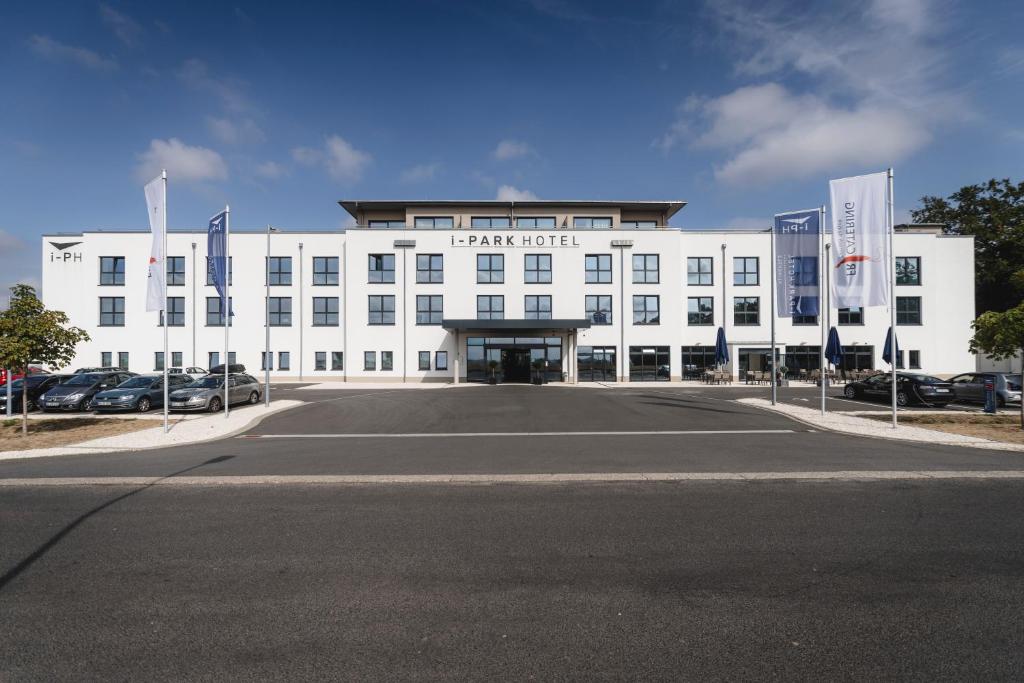 a large white building with a parking lot in front at i - PARK Hotel Klingholz in Reichenberg