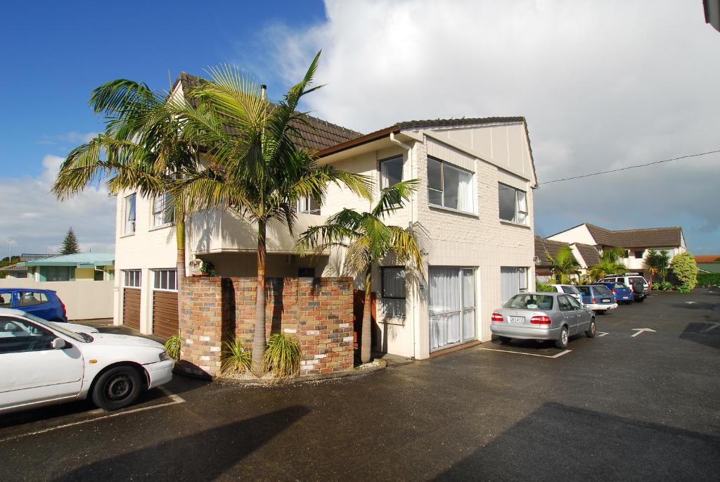 a house with a palm tree in a parking lot at Takapuna Motor Lodge in Auckland