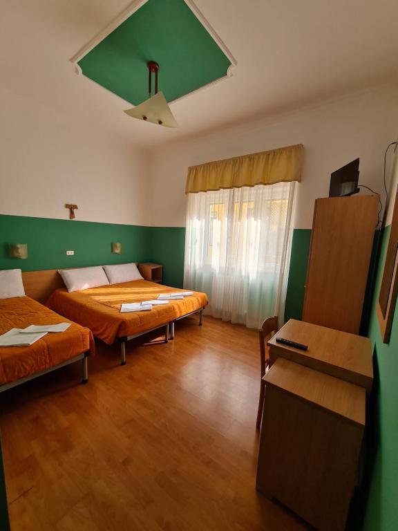 2 łóżka w pokoju z zielonymi ścianami i drewnianą podłogą w obiekcie B&B Santa Lucia w mieście San Giovanni Rotondo