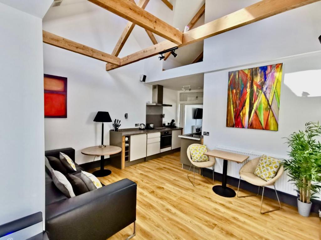 a living room with a black couch and a kitchen at Seashells at 2 TRENCROM COURT ST IVES in Carbis Bay