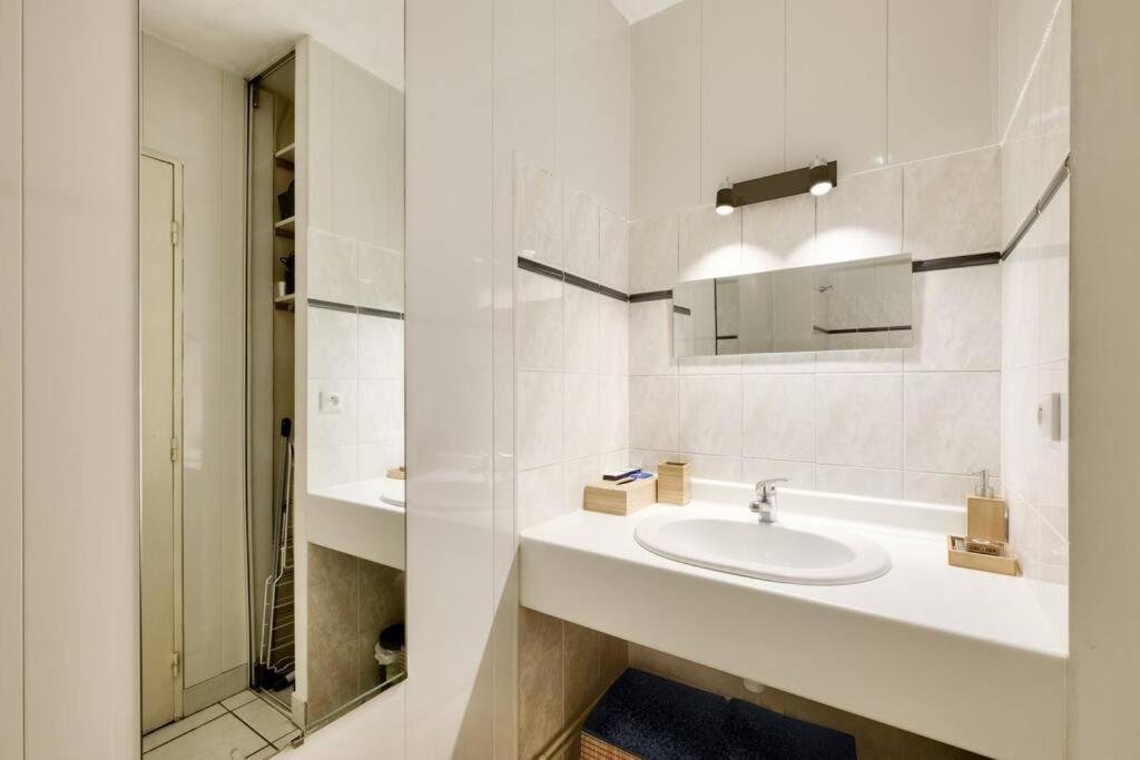 a white bathroom with a sink and a mirror at Studio cosy idéal pour 2 personnes situé à Lyon in Lyon