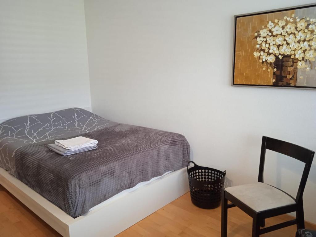 1 dormitorio con 1 cama, 1 silla y 1 foto en Studio flat in the heart of Zug, ideal for solo travellers, en Zug