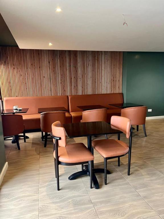 a waiting room with chairs and a table and a table and chairs at Kozi Suites Nairobi Airport in Nairobi