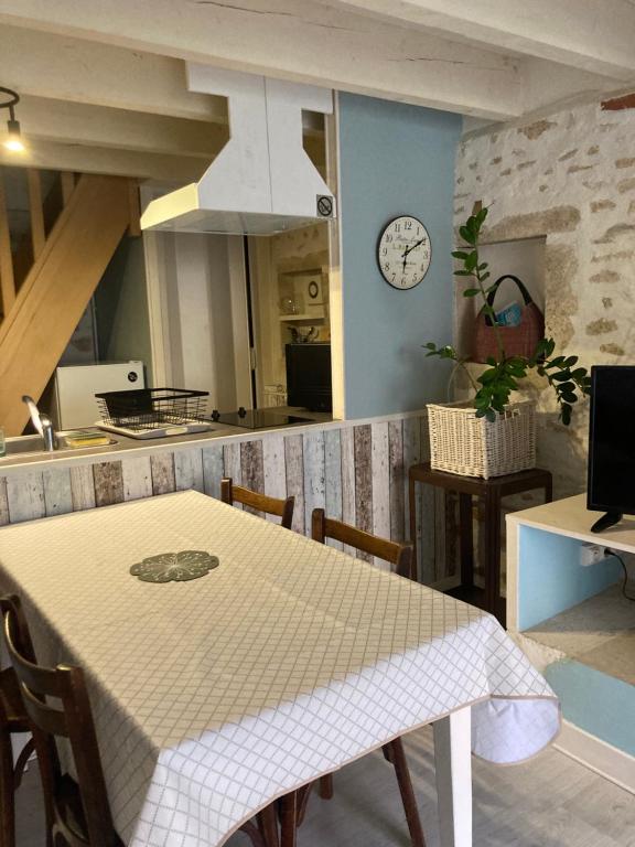 a kitchen with a table and a clock on the wall at Logis côté Jardin in Varennes-lès-Narcy