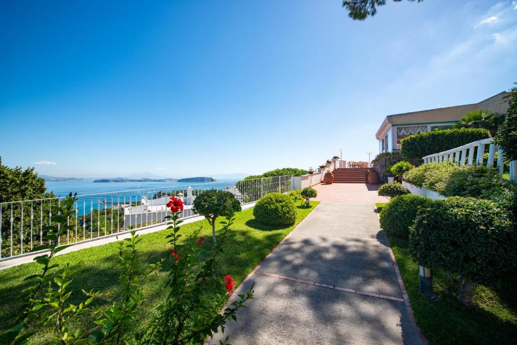 a walkway through a garden with a view of the water at Hotel Villa Ireos in Ischia