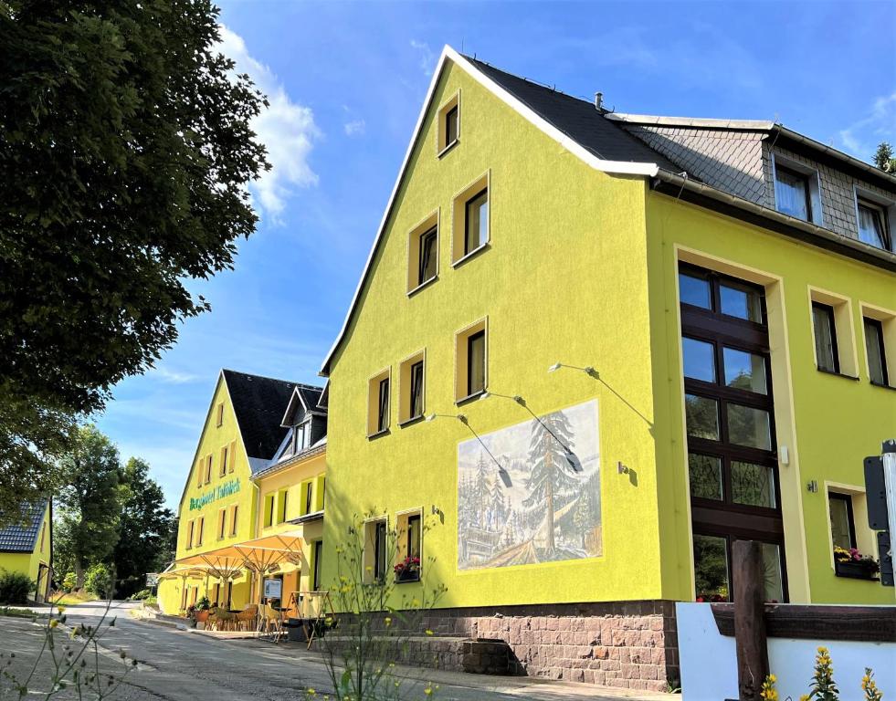 un edificio amarillo con una pintura a un lado en Berghotel Talblick, en Holzhau
