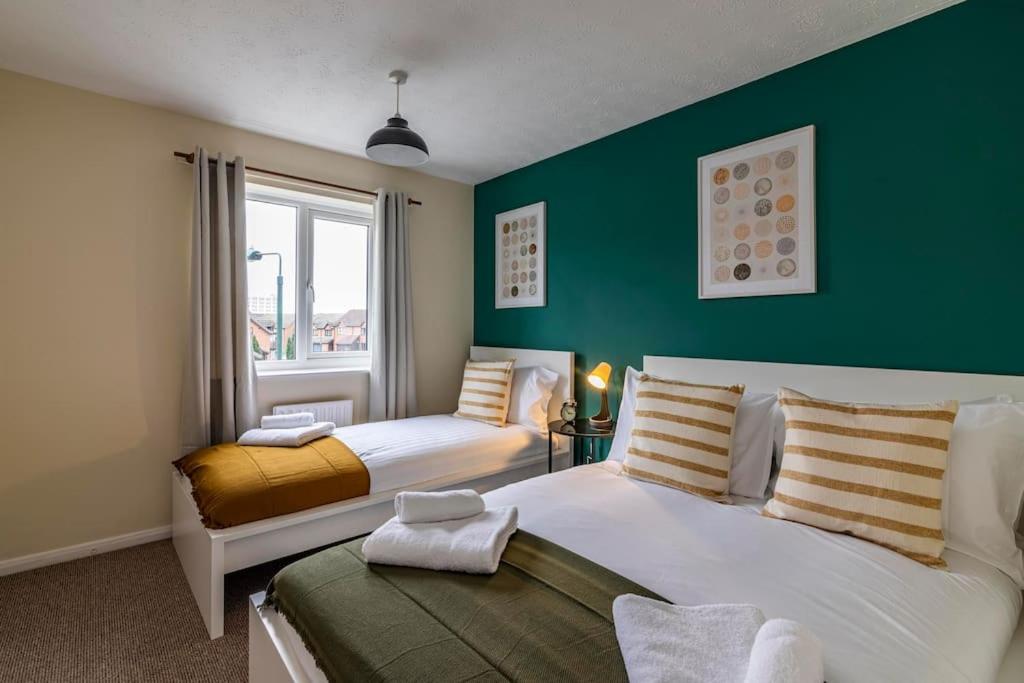 a bedroom with two beds and a green wall at Heron House 2 Bedrooms, Private Garden FREE PARKING, Close to City, Hospital and Uni Long Stays Welcome in Nottingham
