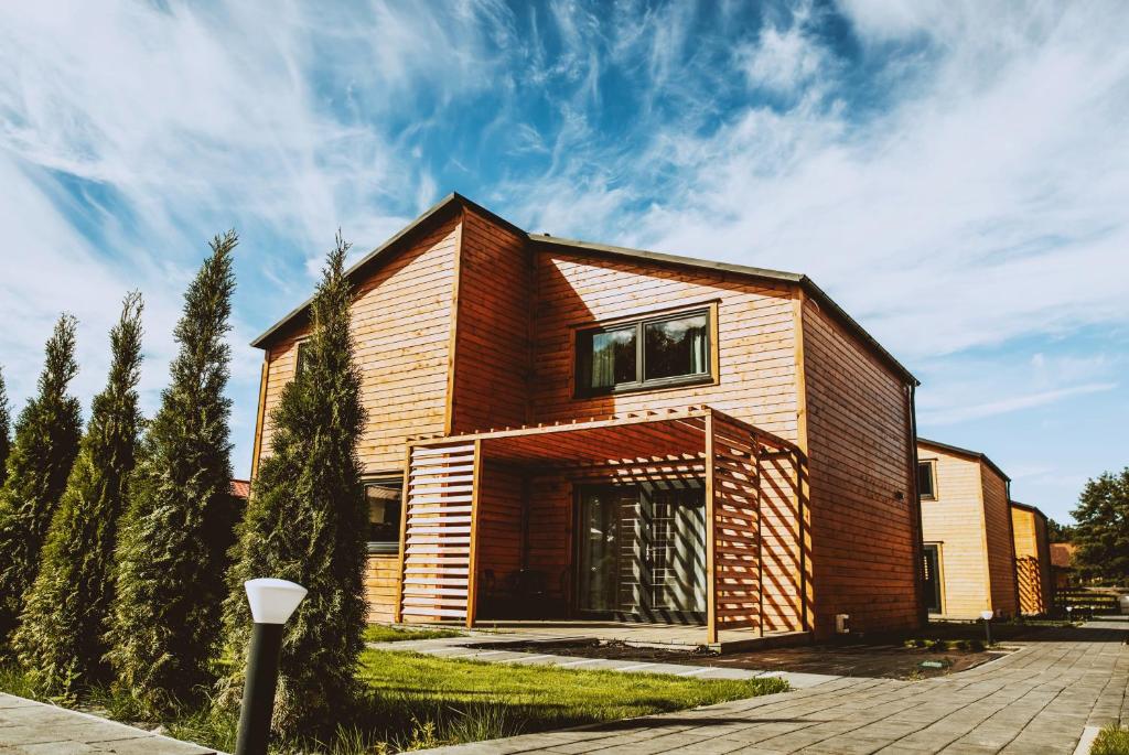 a house with a wooden facade at Baltica Mielenko - domki apartamentowe nad morzem in Mielenko