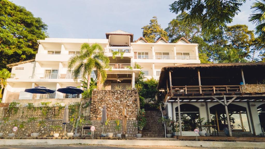 un grand bâtiment blanc avec des parasols en face de celui-ci dans l'établissement Saravoan-Kep Hotel, à Kep