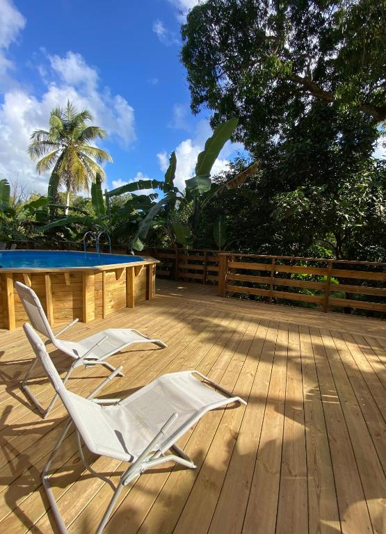 two white lawn chairs sitting on a wooden deck at Ti bambou nature in Sainte-Anne