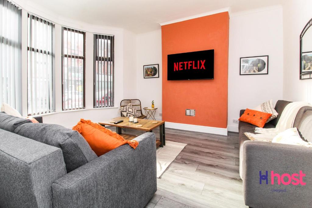 a living room with two couches and an orange accent wall at Host Liverpool - Spacious family home pets welcome in Liverpool