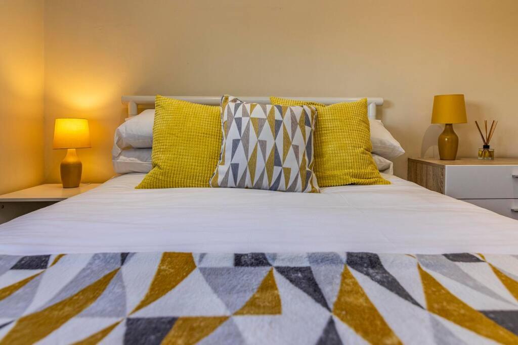 un grande letto con cuscini gialli e blu sopra di Percy House Cosy 2 Bedroom Home, Private Garden FREE PARKING Long Stays welcome a Nottingham