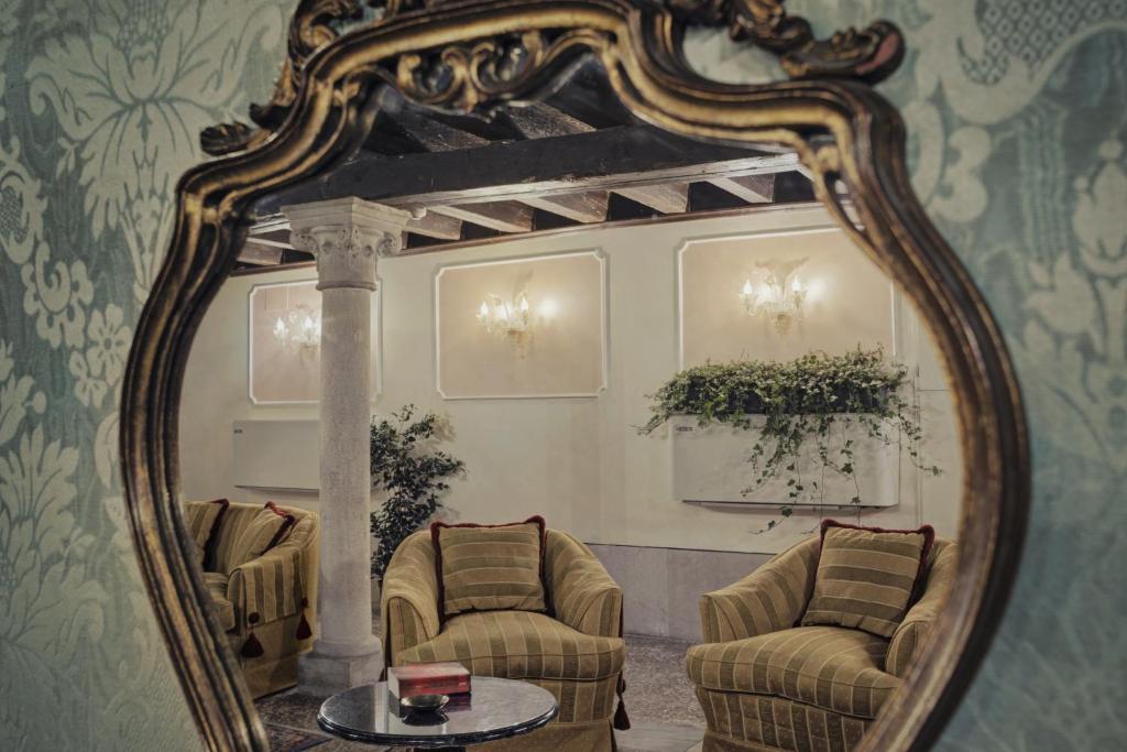 a mirror in a room with two chairs and a table at Hotel Pausania in Venice