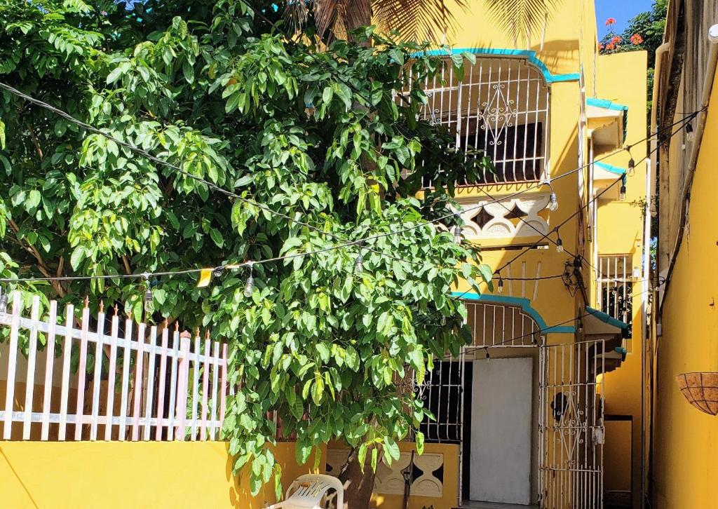 a yellow building with a tree next to a white fence at The Tea House in San Juan