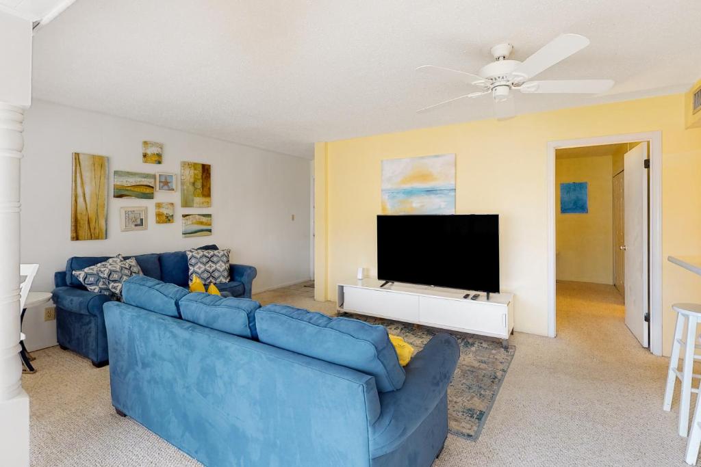 sala de estar con sofá azul y TV de pantalla plana en Gulf Terrace 126 en Destin