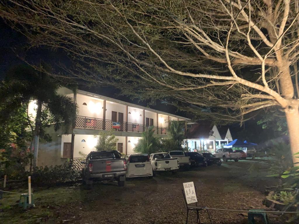 RTMS Guesthouse Semporna في سيمبورنا: مبنى فيه سيارات تقف امامه ليلا