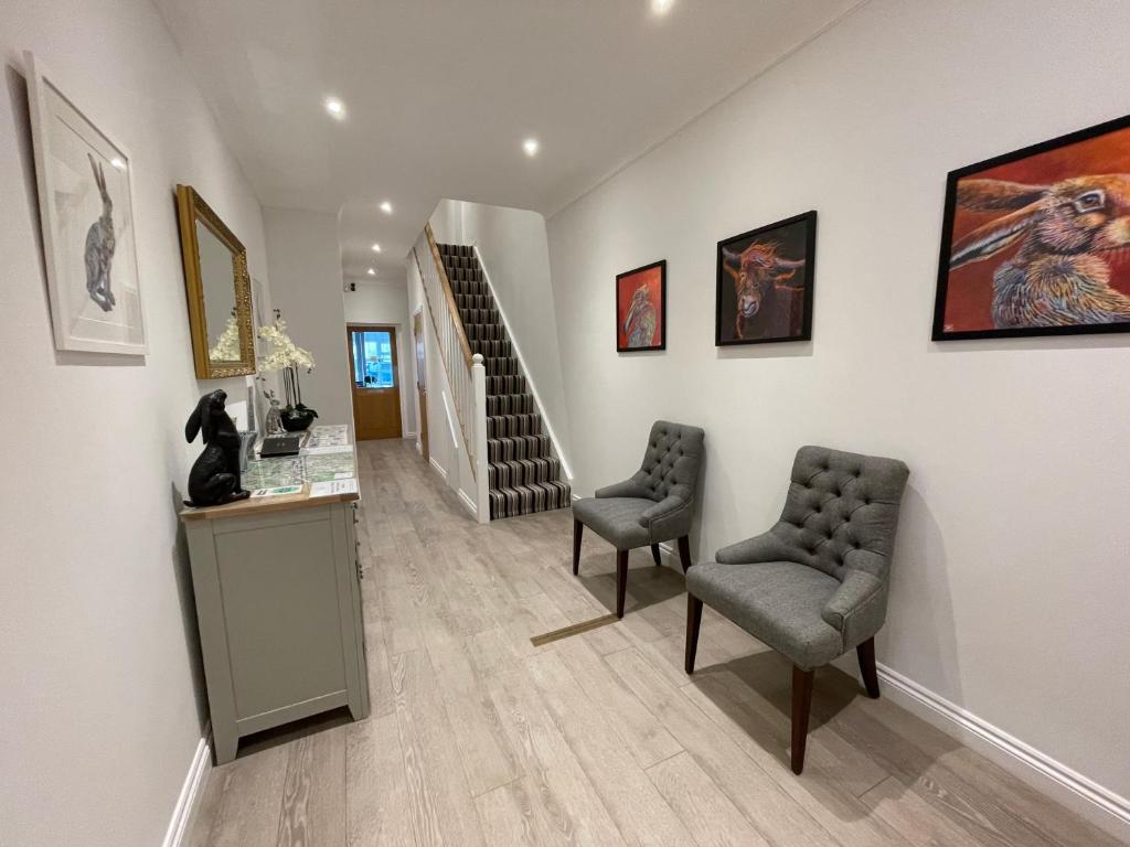 a hallway with two chairs and paintings on the wall at Cotswold Hare in Cirencester