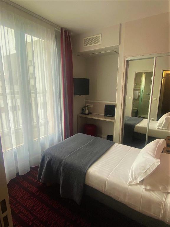 ein Hotelzimmer mit einem Bett und einem Spiegel in der Unterkunft Hotel Le Richemont in Paris