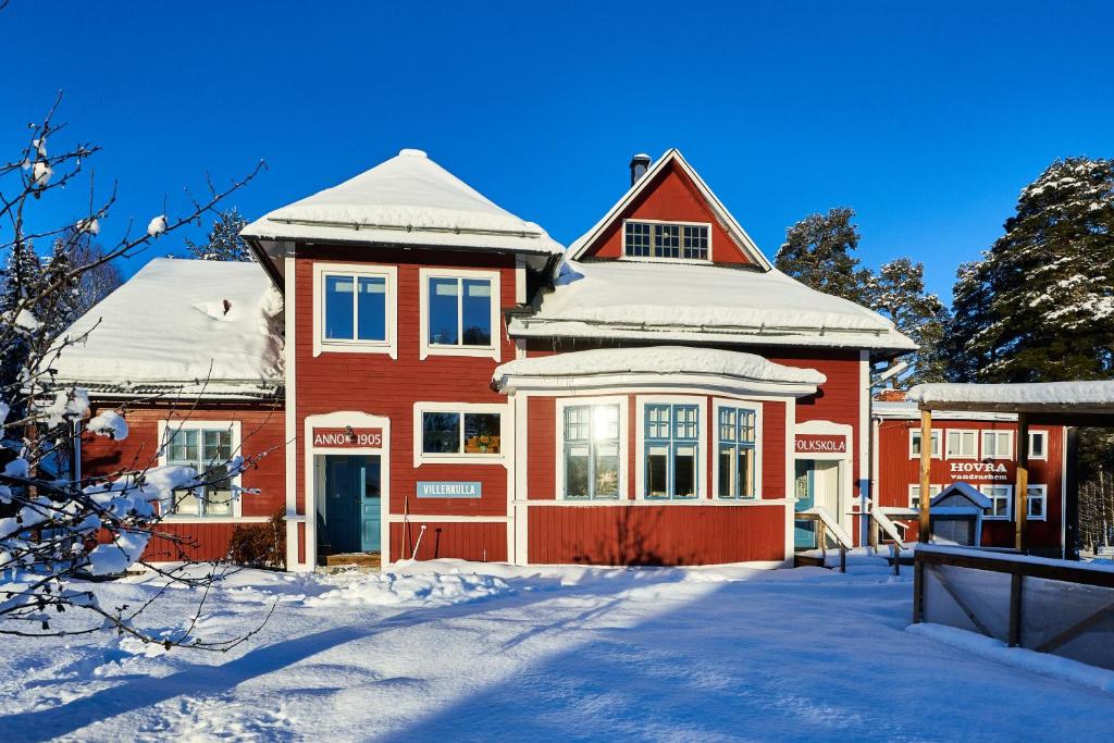 Korskrogen的住宿－Hovra Vandrarhem，一座红房子,上面有雪