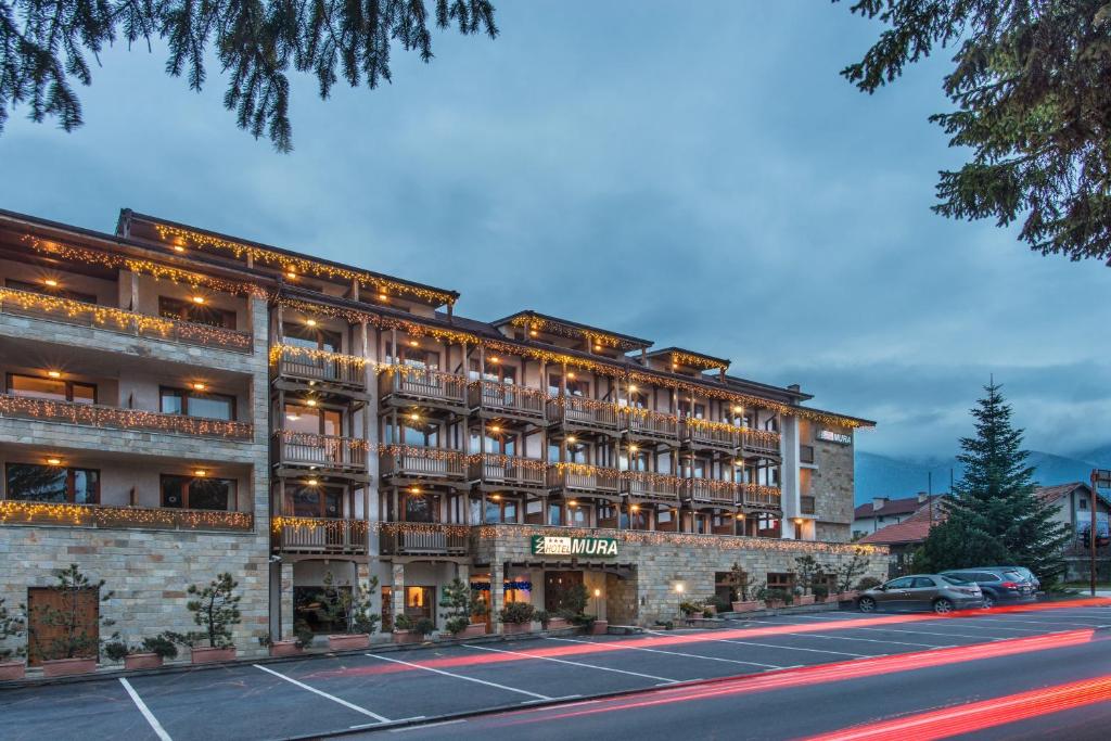 a large building with a parking lot in front of it at Mura Hotel in Bansko