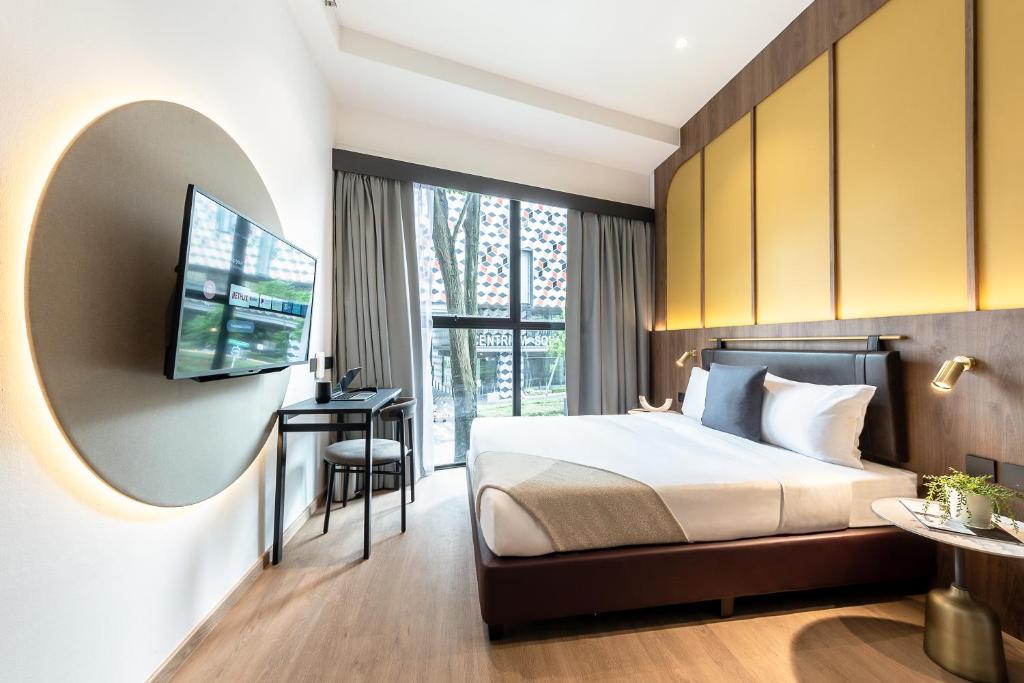 a bedroom with a bed and a flat screen tv at Owen House by Habyt in Singapore