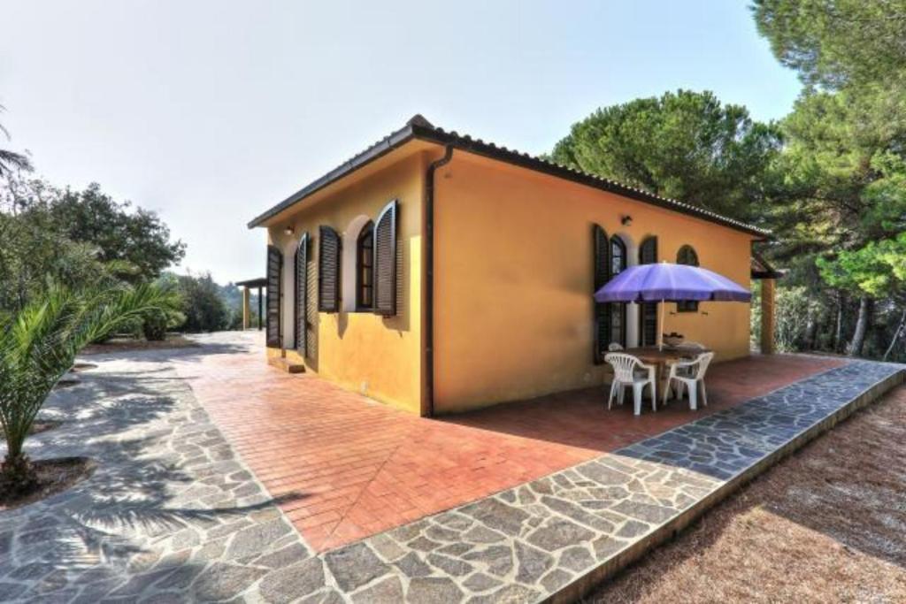 a house with a patio with a table and an umbrella at Capoliveri: Villa Artistica app. 2/bilo4 (bilocale in Capoliveri