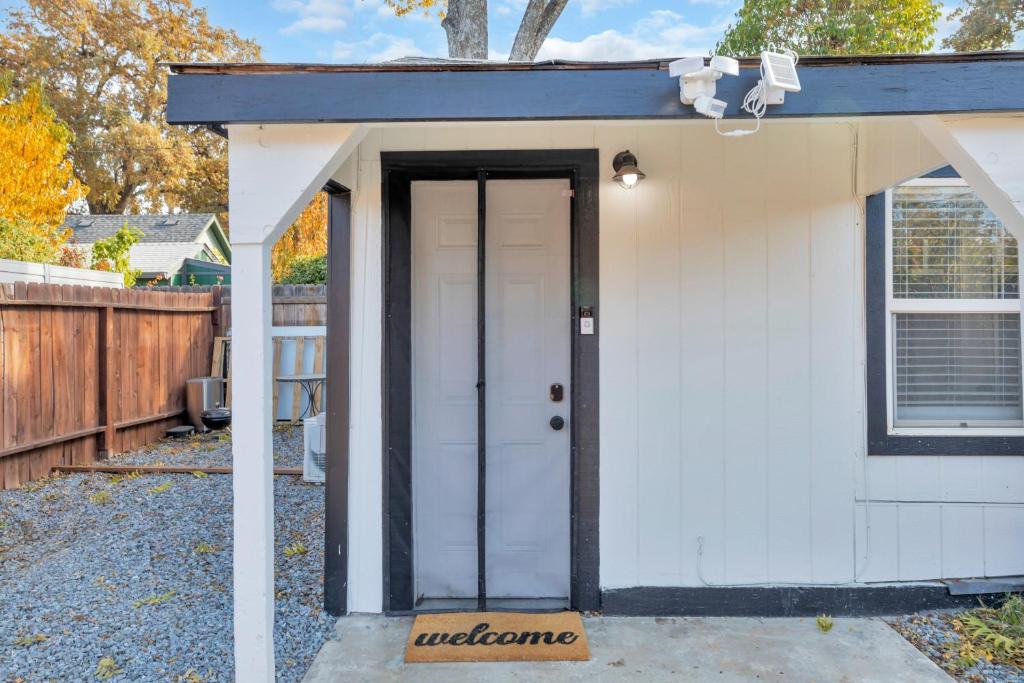 een kleine witte schuur met een deur in een tuin bij A Cottage - Walk to UC Davis & Shriners in Sacramento