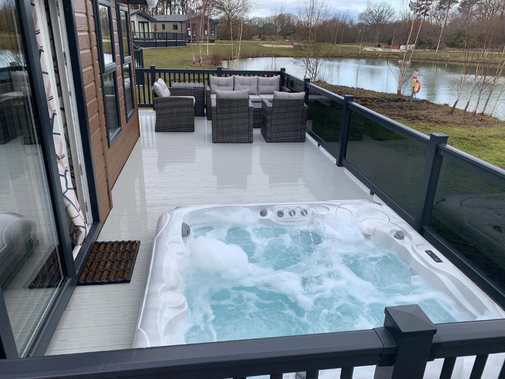 a jacuzzi tub on the deck of a house at Bay Tree Lodge: Lakeside lodge w/hot tub & cinema surround sound in Woodhall Spa