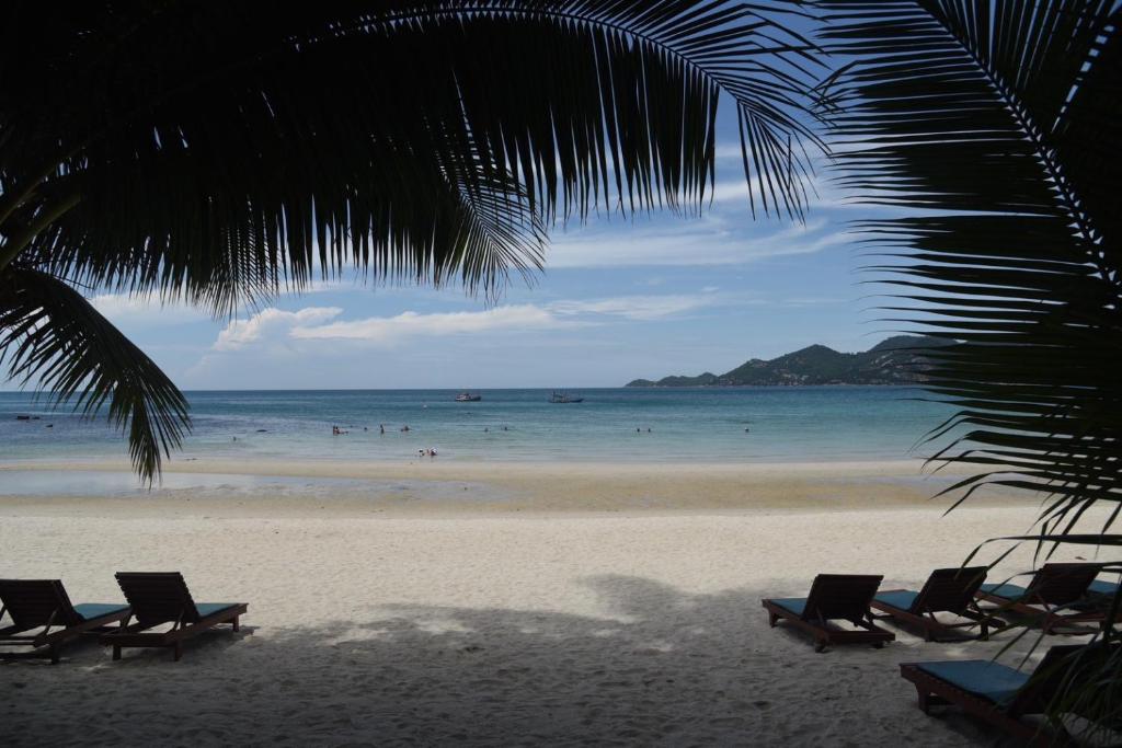 - une plage avec des chaises et des personnes dans l'océan dans l'établissement Coconut House Resort, à Koh Samui 