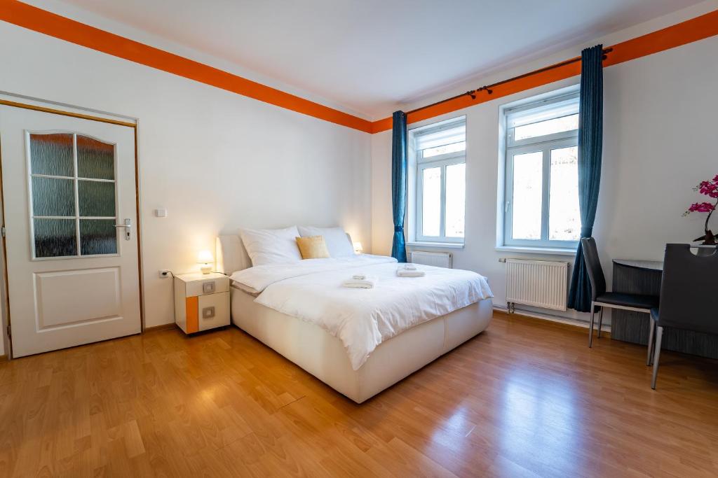 a bedroom with a large white bed and a desk at Tuan Long Apartments in Jáchymov