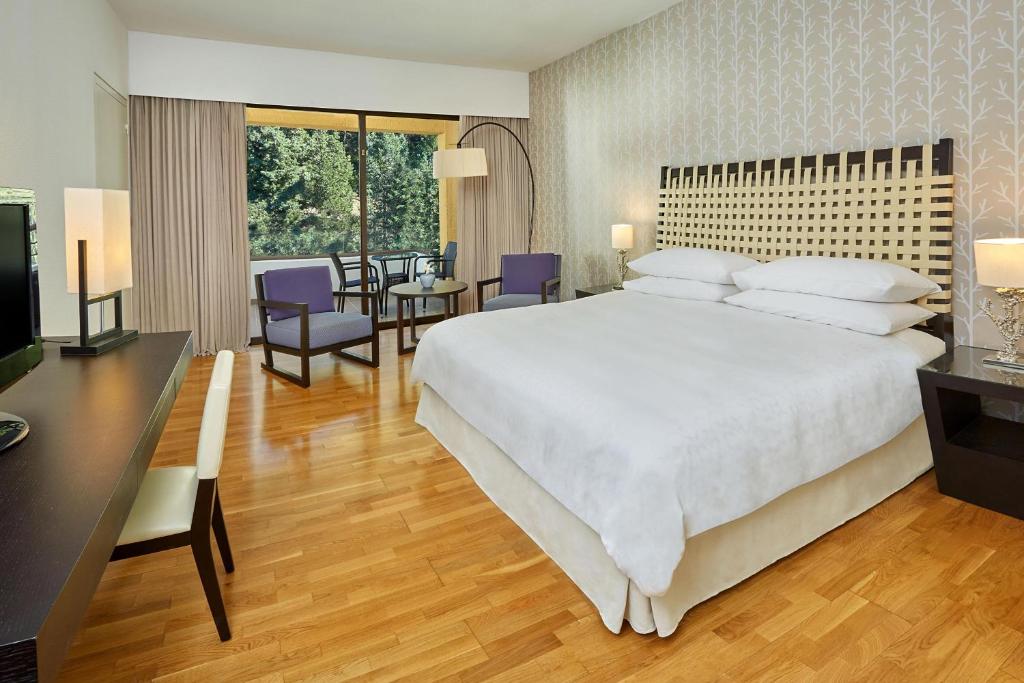 a bedroom with a large bed and a dining room at Sheraton Rhodes Resort in Ixia