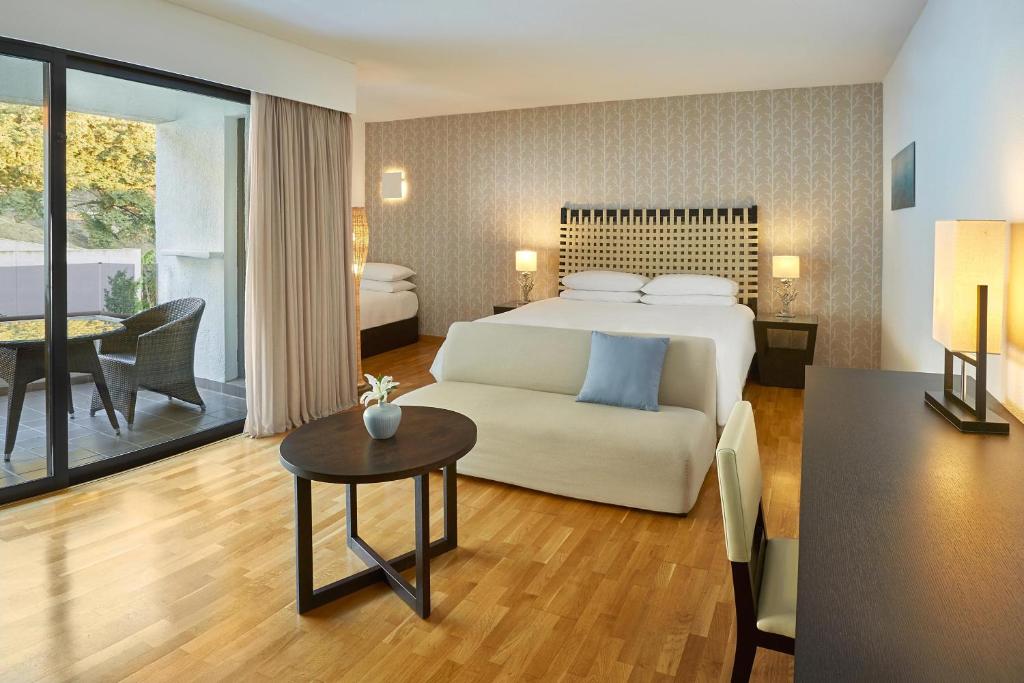 a hotel room with a bed and a table at Sheraton Rhodes Resort in Ixia