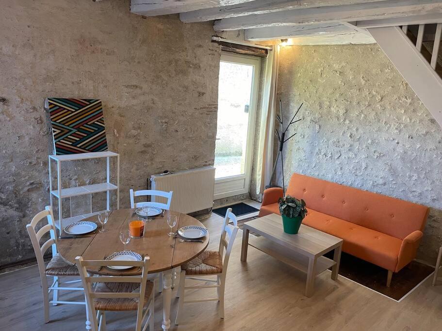 uma sala de estar com uma mesa e um sofá em Gite Le Baulois, maisonnette calme et confort en vallée de Loire em Baule
