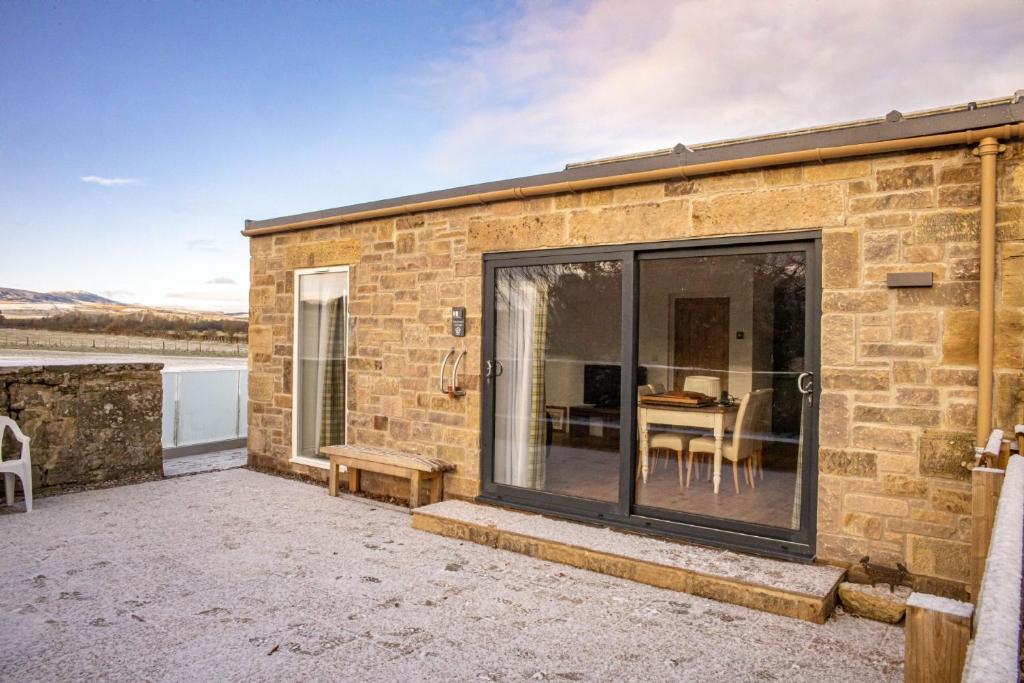 a brick house with a large sliding glass door at Gardener's Cottage in Alnwick