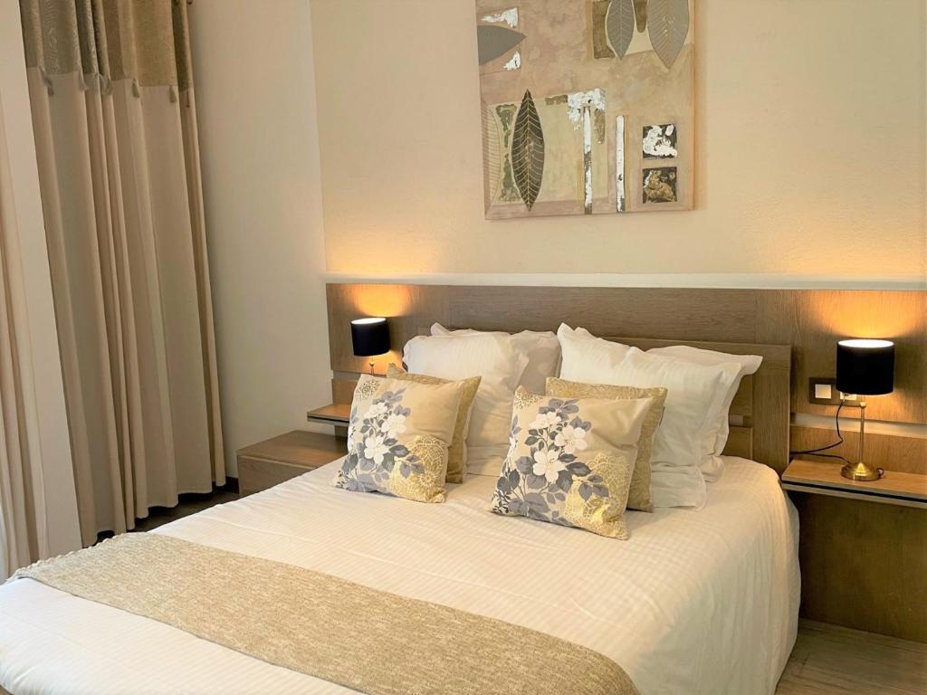 a bedroom with a bed with white sheets and pillows at Hôtel Le Méditerranée in Hyères