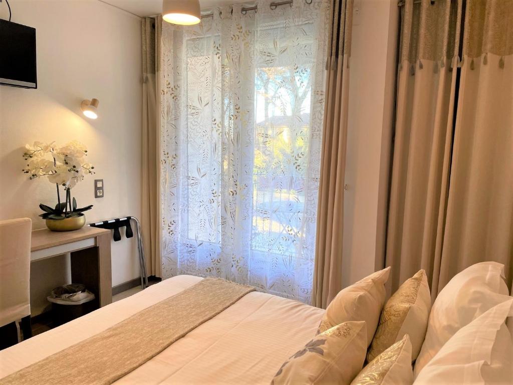 a bedroom with a bed and a window with curtains at Hôtel Le Méditerranée in Hyères