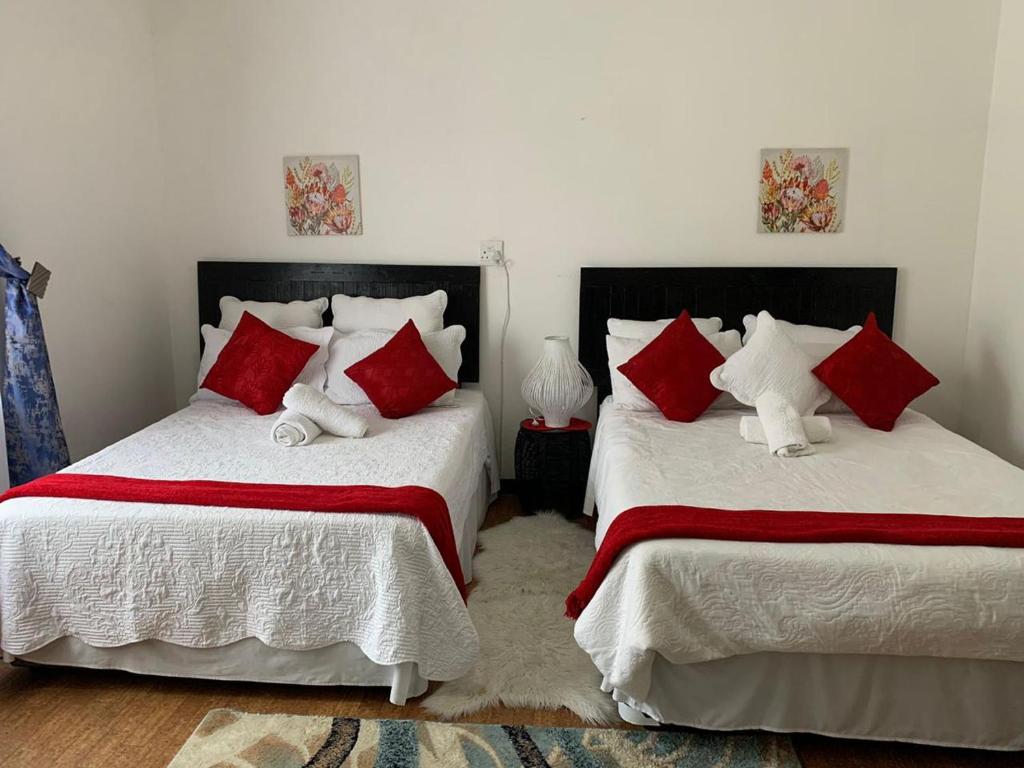 a bedroom with two beds with red and white pillows at TSGuesthouse in Margate