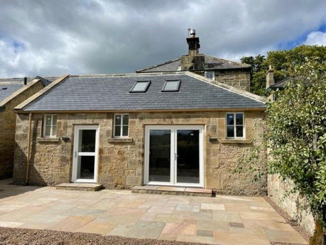 a stone house with two windows and a roof at The Kennelman 2 bedroom option in Alnwick