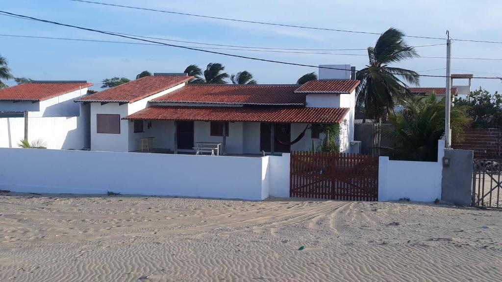 una casa en la playa con una valla blanca en Casa do Kite en Galinhos