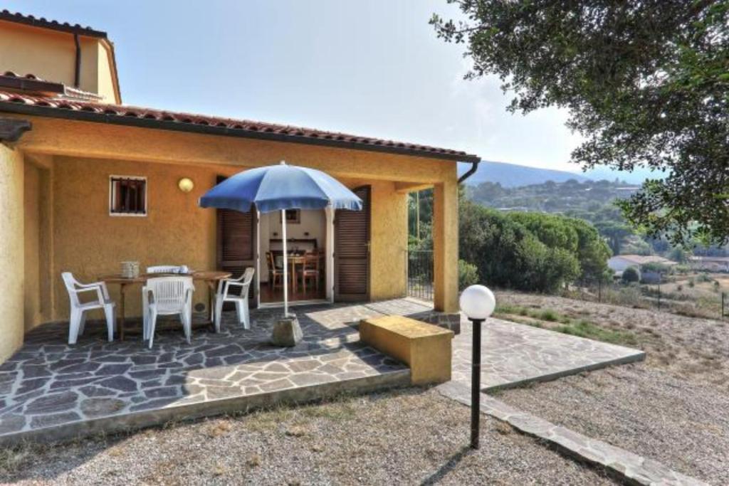 a patio with a table and an umbrella in front of a house at Villa Artistica trilo 3 in Capoliveri