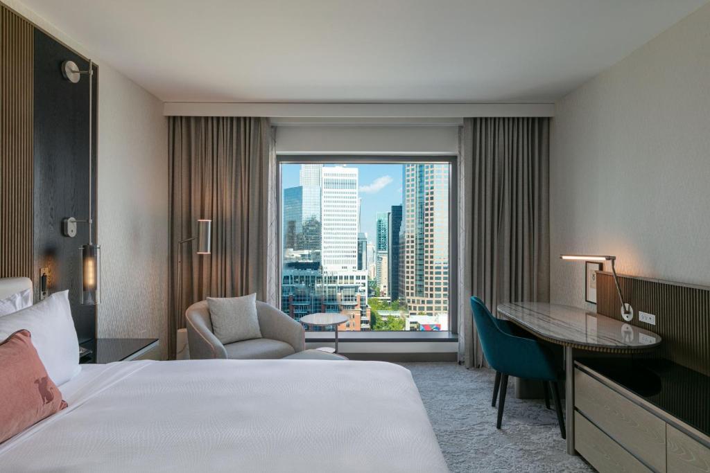 シャーロットにあるJW Marriott Charlotteのベッド、デスク、窓が備わるホテルルームです。
