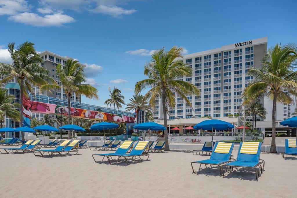 ein Strand mit Stühlen und Palmen und ein Hotel in der Unterkunft The Westin Fort Lauderdale Beach Resort in Fort Lauderdale