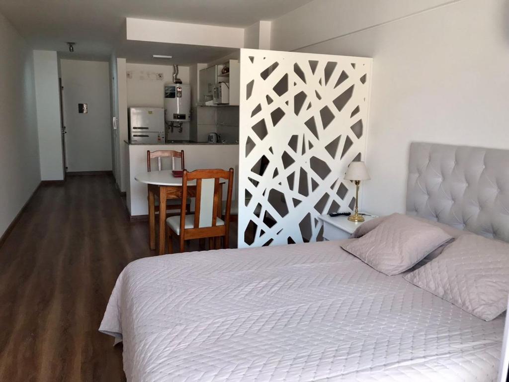 1 dormitorio con 1 cama blanca y cocina en Rosarioalquilertemporario en Rosario