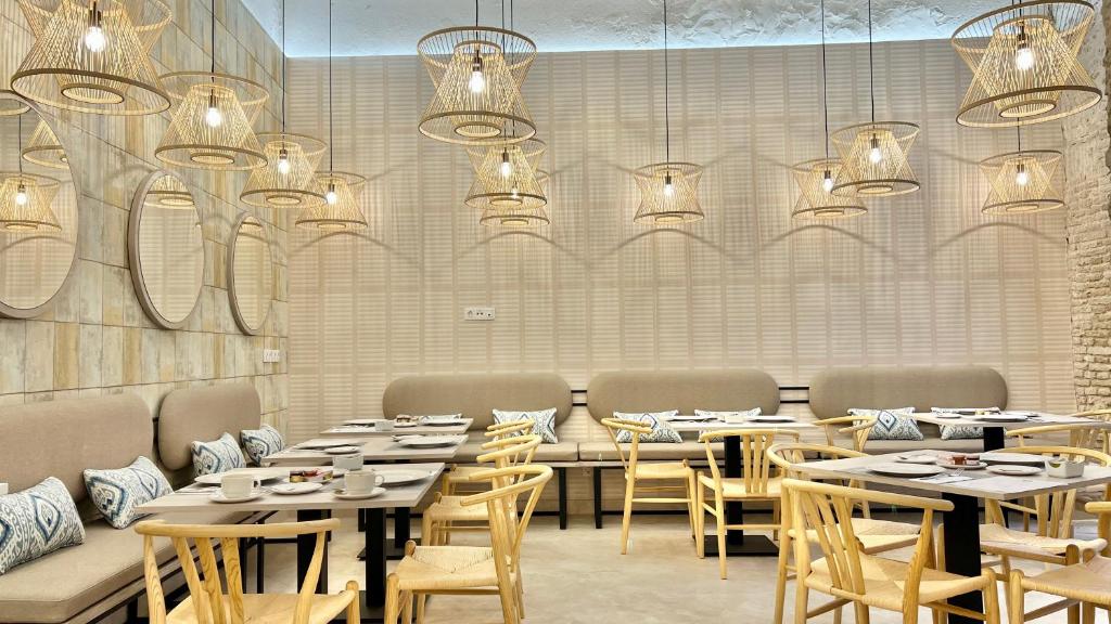 a dining room with tables and chairs and chandeliers at Soho Boutique Cádiz in Cádiz