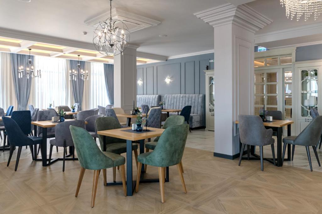 un restaurante con mesas y sillas y una lámpara de araña en Aquamarine - Wellness & SPA Hotel, en Kranevo