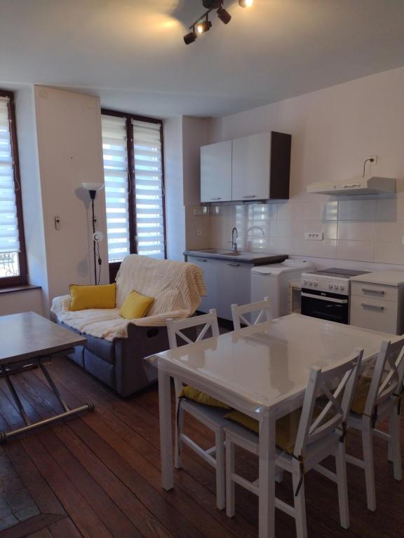 eine Küche und ein Wohnzimmer mit einem Sofa und einem Tisch in der Unterkunft Appartement 1er etage proche des Termes in Bourbonne-les-Bains
